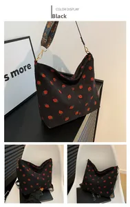 Detail of black corduroy bucket bag with strawberry patterns and colorful jacquard strap