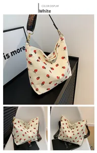 Close-up of white corduroy bucket bag featuring strawberry pattern and colorful wide strap