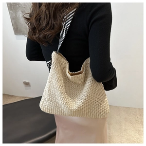 Detail der handgewebten beigen Strohtasche mit schwarz-weiß gestreiftem Schultergurt