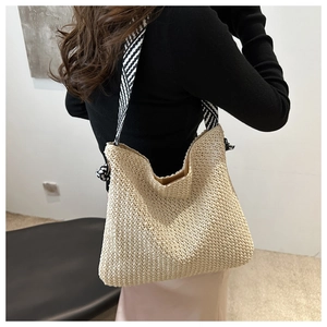 Detail der handgewebten Strohtasche mit schwarz-weißem Schultergurt aus Seidenschal
