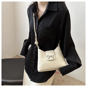 Détail du sac seau en cuir blanc crème avec nœud argenté et bandoulière en corde tressée