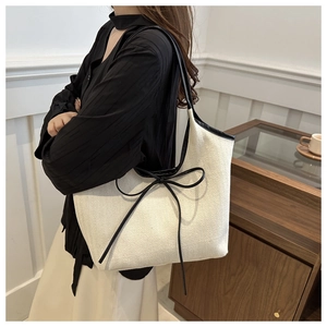 Détail du sac cabas en lin avec texture zigzag, sangle en cuir noir et nœud décoratif