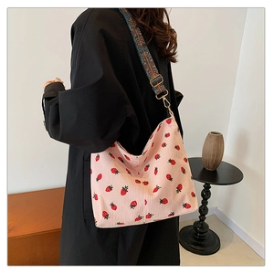 Detail of pink corduroy tote bag with strawberry embroidery and ethnic woven strap