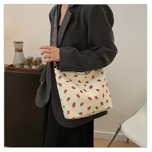 Detail of strawberry corduroy tote bag with colorful geometric woven shoulder strap