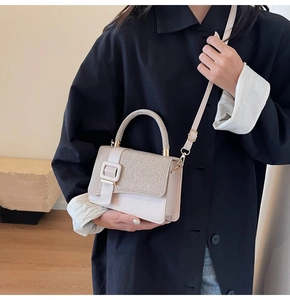 Chic beige textured crossbody bag with square buckle shown on a black coat outfit