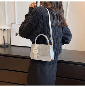 Détail du rabat à paillettes argentées et texture cuir blanc du sac à bandoulière chic