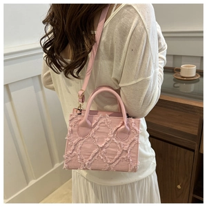 Borsa a tracolla in denim rosa con frange indossata da modella in interni caldi