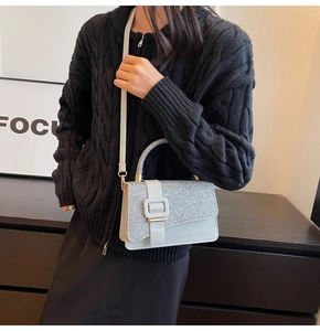 Close-up of silver sequined square bag with a metallic buckle and leather shoulder strap