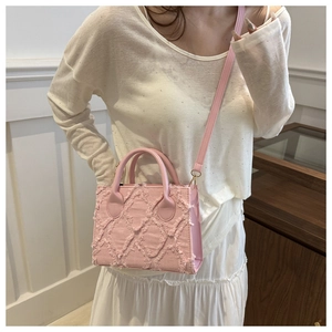 Dettaglio della borsa a tracolla in denim rosa con trame a frange e finiture dorate