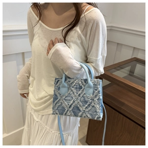 Dettaglio borsa in denim azzurro con frange a taglio vivo e trama trapuntata elegante