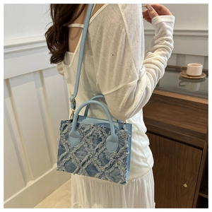 Dettaglio della borsa in denim azzurro con nappe, motivo trapuntato e finiture oro