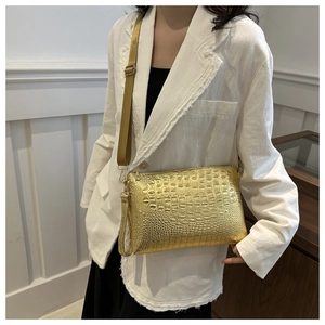 Detail of gold crocodile embossed envelope bag with metallic texture and dual straps