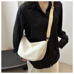 Detail of off-white hobo bag showing woven texture and adjustable fabric shoulder strap