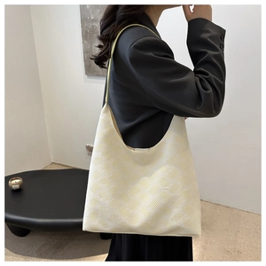 Gros plan sur la texture géométrique en maille et le tissu doux d'un sac bandoulière crème