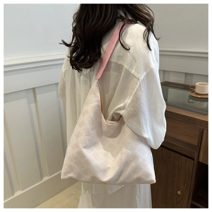 Détail du sac fourre-tout tissé rose avec bandoulière en cuir porté par un mannequin