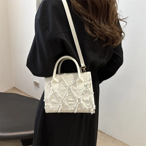 Borsa tote in denim bianco con frange e trama trapuntata indossata da una modella