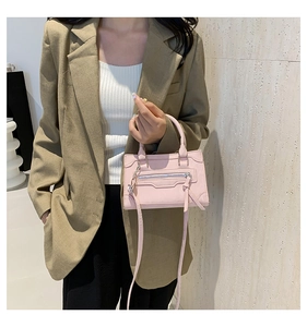 Detailed view of pink trapezoid handbag with long zipper tassels and crossbody strap