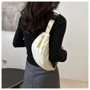 Detail of minimalist cream crossbody bag featuring textured geometric woven patterns and zipper