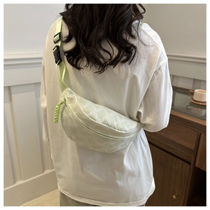 Rear view of pistachio green striped crossbody bag with textured woven surface on model