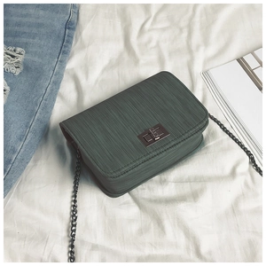 Detail of dark green textured flap bag with silver metal swivel lock and chain strap