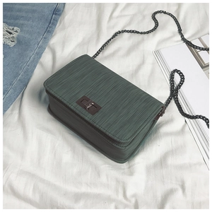 Detail of dark green textured leather shoulder bag with vintage metal twist lock closure