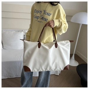 Close-up of white waterproof tote bag featuring brown leather handles and corner accents