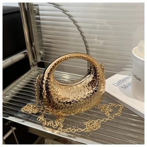 Close-up of gold metal evening clutch with textured surface and chain strap