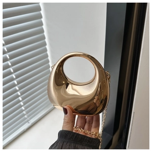 Close-up of a crescent-shaped gold mirror finish clutch bag with a round cut-out handle