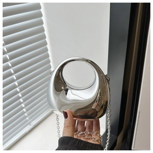 Close-up of a silver mirror finish mini bag with an oval cutout handle and metal chain