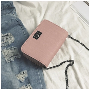 Detail of light pink square bag with dark grey metal turn lock and chain strap