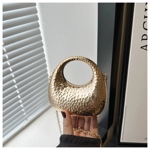 Close-up of golden hammered metal evening clutch with round handle and gold chain strap
