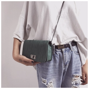 Detailed view of dark green crossbody bag with vertical textures and metal twist lock