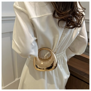 Polished gold metal mini bag featuring a sleek circular design and slim chain strap