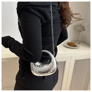 Detail of silver crescent bag featuring a hammered texture and delicate metal chain strap