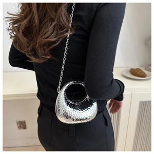 Detail of silver metallic hobo bag featuring hammered texture and circular ring handle