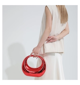 Sac à main rouge métallique moderne au design demi-lune porté par un mannequin