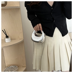 Chic silver crescent evening bag with hammered metal texture held by a hand