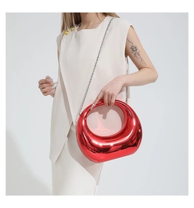 Détail d'un sac à main rouge effet miroir avec une élégante bandoulière en chaîne argent