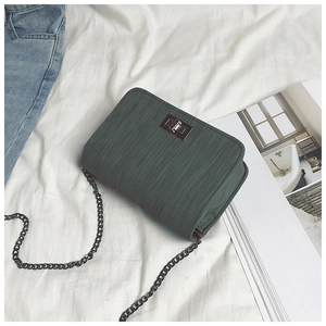 Detail of dark green square bag featuring vertical stripes and gunmetal twist lock