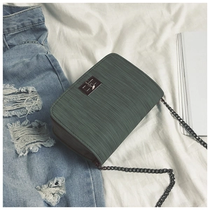 Close-up of dark green square chain bag with gunmetal twist lock on white fabric