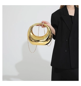 Gros plan d'un sac à main en métal doré en forme de croissant avec bandoulière chaîne