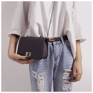 Detail of compact black chain crossbody bag featuring a silver square twist-lock closure