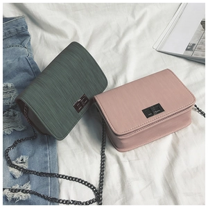 Detail of minimalist leather crossbody bags with metal twist locks and chain straps