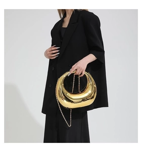 Détail d'un sac à main en forme de croissant doré miroir avec une bandoulière chaîne