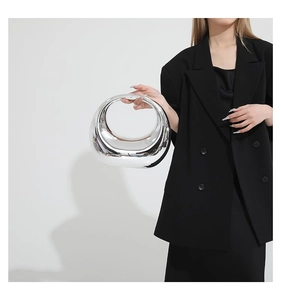 Détail d'un sac à main argenté à effet miroir et design demi-lune porté par un mannequin