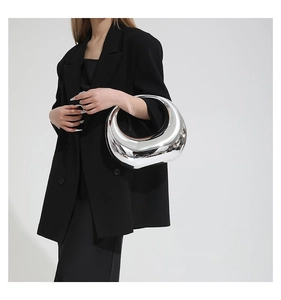 Sac demi-lune argenté miroir au fini métallique porté avec un blazer noir