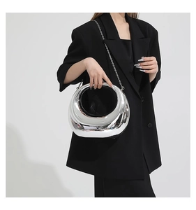 Gros plan d'un sac à main ovale argenté effet miroir avec une fine chaîne en métal
