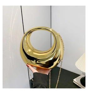 Détail d'un sac à main demi-lune doré métallisé avec poignée ronde et chaîne dorée