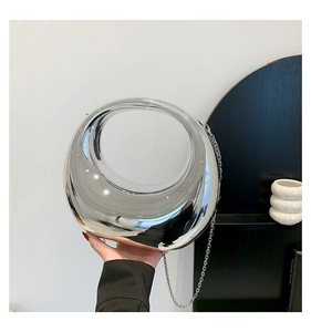 Détail d'un sac à main argenté miroir futuriste avec une découpe circulaire irrégulière