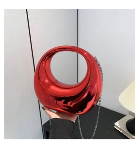 Détail d'un sac de soirée rouge métallique avec poignée ronde et chaîne fine